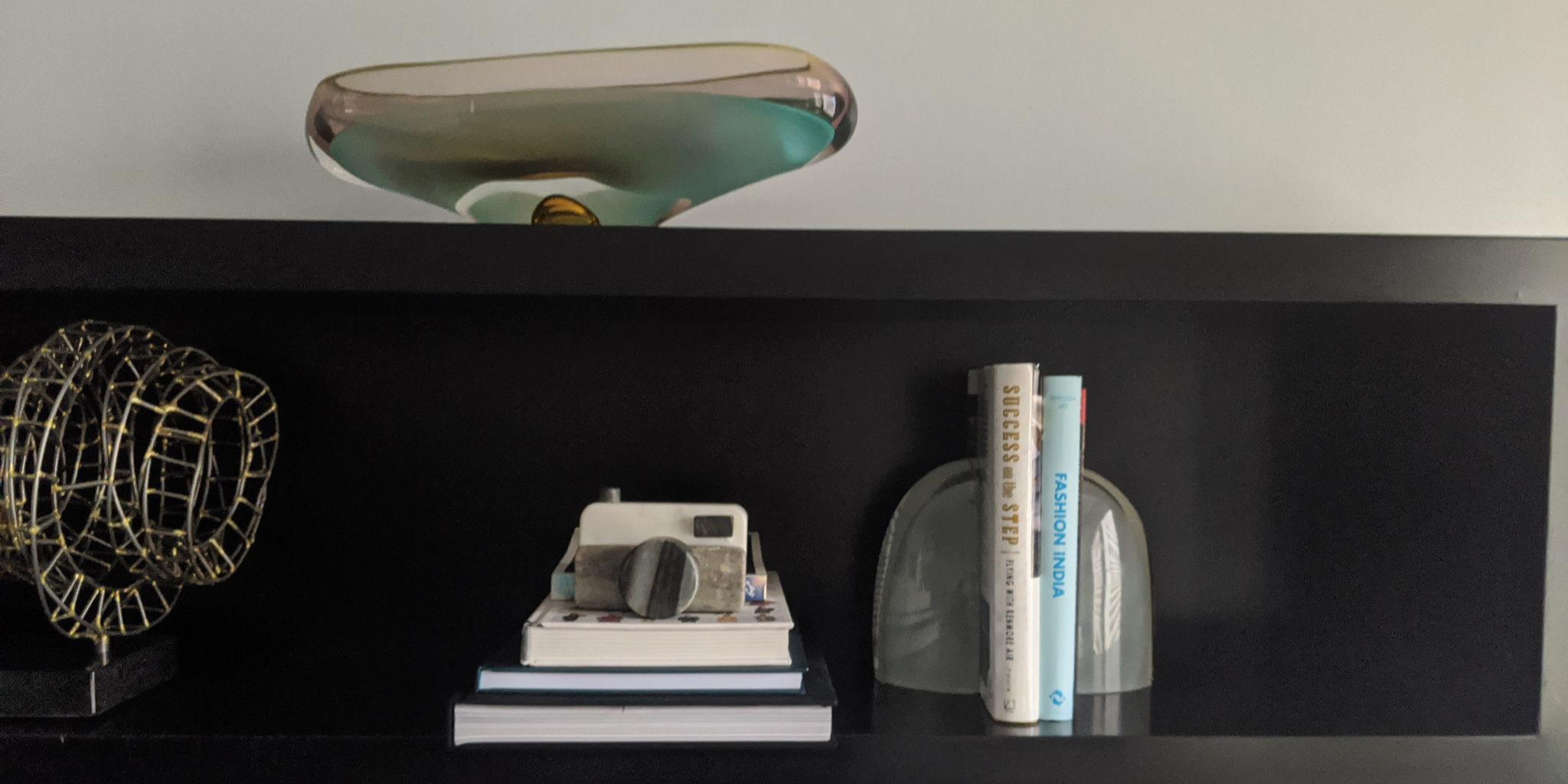 Organized shelf with only a few books and artwork to make it look less cluttered